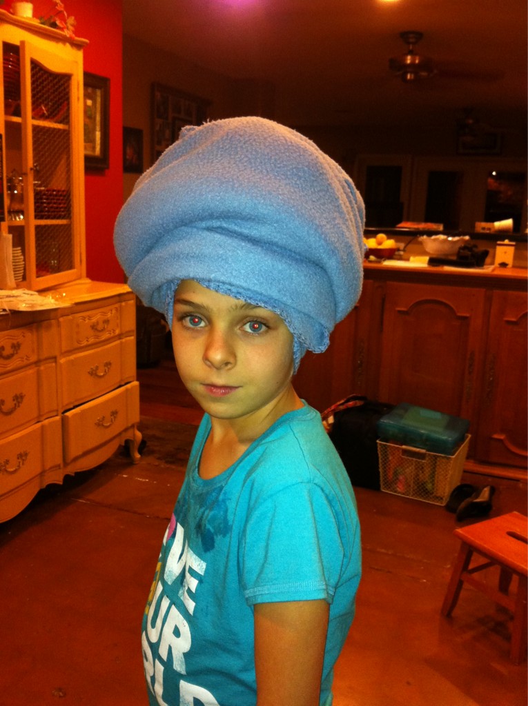 A young girl with a purple felt blanket wrapped around her hed like a large turban.