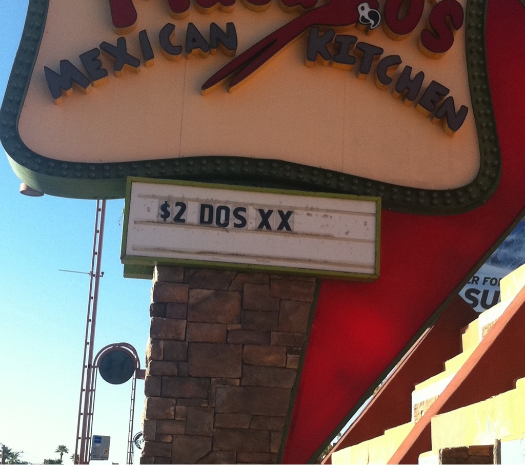 A letter-board sign on a restaurant that reads "$2 Dos XX".